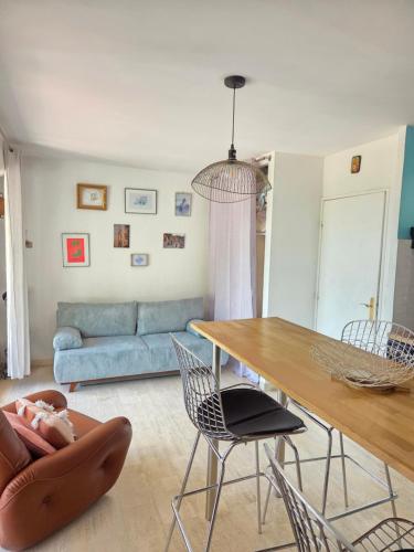 un salon avec une table, des chaises et un canapé dans l'établissement Charmant studio terrasse avec vue, plein sud, à Nîmes
