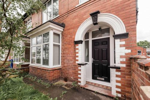 a brick house with a black door and windows at Spacious 4 Bedroom House with Garden in Doncaster in Doncaster