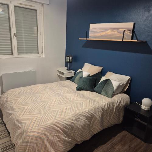 une chambre avec un lit avec un mur bleu dans l'établissement Le Cardinal, à Pessac