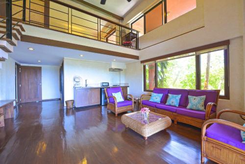 Una sala de estar con un sofá morado y una mesa. en Biancas Garden Apartments Boracay, en Boracay