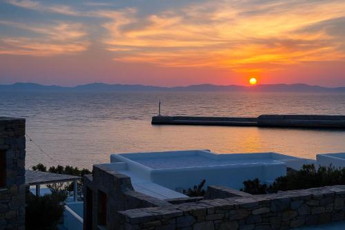 a sunset over a body of water with a pier at Mykonos Seaview Nests - Tourlos Getaways in Tourlos