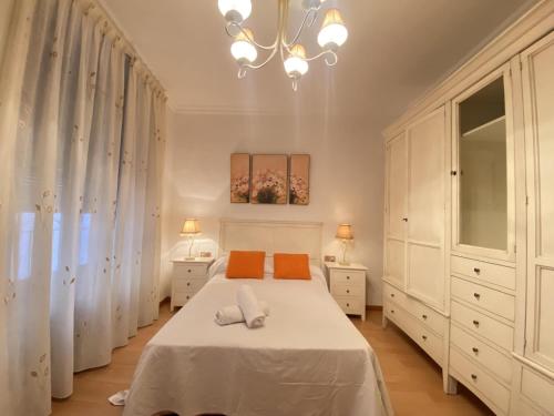 TH61 Apartamento vacacional Plaza de la Font في تاراغونا: غرفة نوم بسرير أبيض وثريا