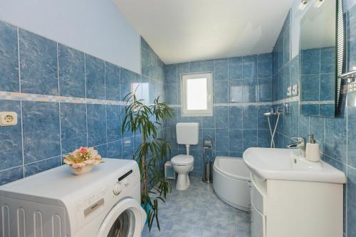 bagno piastrellato blu con lavatrice di Apartman Lucija a Kaštela (Castelli)
