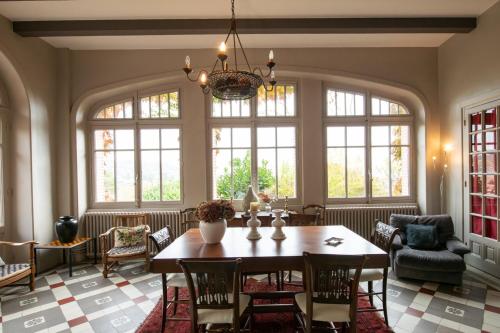 une salle à manger avec une table, des chaises et des fenêtres dans l'établissement La croix des Rameaux- charming house near Lyon, à Saint-Didier-au-Mont-dʼOr