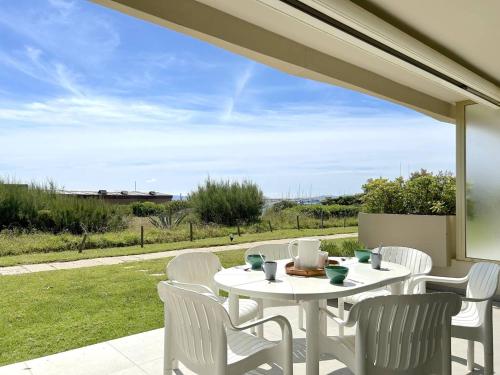 - une table et des chaises blanches sur la terrasse dans l'établissement Appartement 3 pièces 4 couchages avec parking au Lavandou - FR-1-251-316, au Lavandou