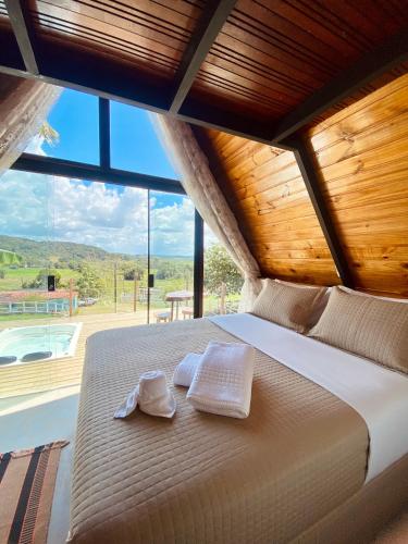 a bed in a room with a large window at Rancho Navarro - Cabana A-Frame in Pôrto de Pedras