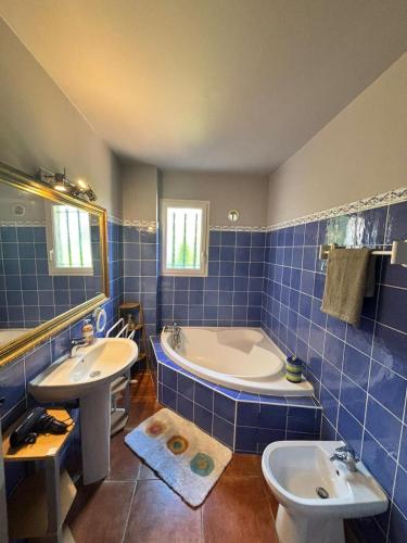 La salle de bains est pourvue de carrelage bleu, d'une baignoire et d'un lavabo. dans l'établissement La maison aux oliviers, à Grasse