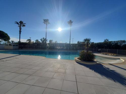 - une piscine avec des palmiers et le soleil dans l'établissement Residence Cap Hermes, Incroyable Vue sur le port,, à Fréjus