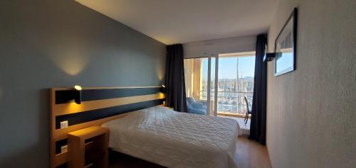 une chambre avec un lit et une grande fenêtre dans l'établissement Residence Cap Hermes, Incroyable Vue sur le port,, à Fréjus
