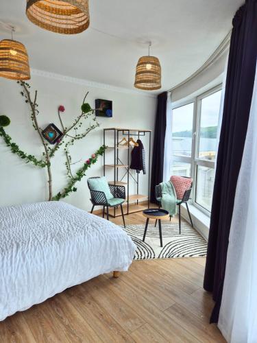 a bedroom with a bed and chairs and a window at L'Eden - Premium Suite - Vue - Balcon in Lourdes