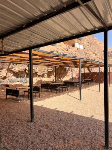 a group of benches sitting under a metal roof at Emma Luxury Camp in Wadi Rum