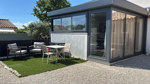 eine Glaserweiterung eines Hauses mit einem Tisch und Stühlen in der Unterkunft Charmant Studio in La Motte-dʼAigues