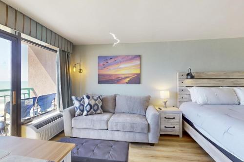 a bedroom with a bed and a couch and a window at Pelicans Flight at Sandcastle South in Myrtle Beach