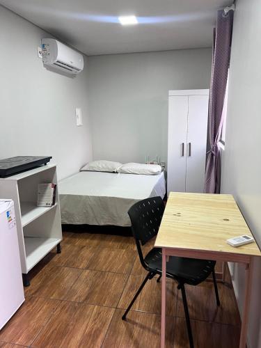 a small room with a table and a bed at Kitinete perto da Itaipu e Unioeste in Foz do Iguaçu