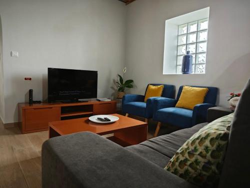 a living room with a couch and a tv at Casa da Marta - Azorean Nature Escape in Nordeste