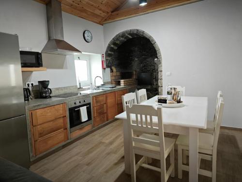 eine Küche mit einem weißen Tisch und Stühlen sowie einem Backofen in der Unterkunft Casa da Marta - Azorean Nature Escape in Nordeste
