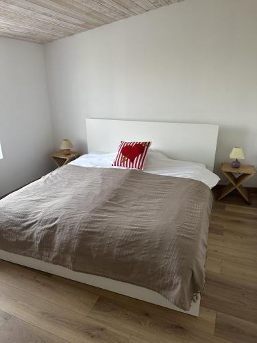 - une chambre blanche avec un grand lit et un oreiller rouge dans l'établissement Maison Bretonne rénovée - Plages et centre à pied, à Camaret-sur-Mer