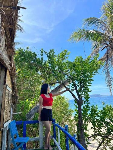 a woman standing on a balcony looking at the ocean at Biển Ngọc Homestay Đảo Bé Lý Sơn in Quang Ngai