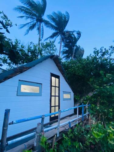 a blue house with palm trees in the background at Biển Ngọc Homestay Đảo Bé Lý Sơn in Quang Ngai