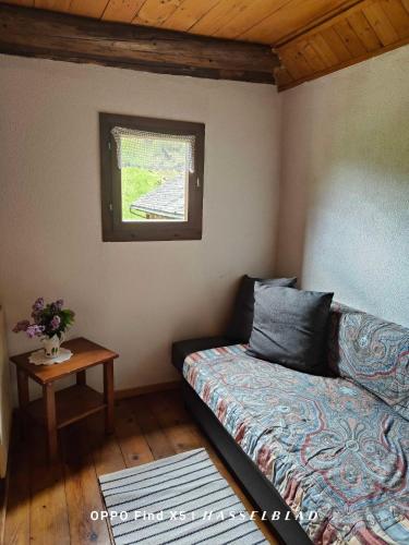 a room with a bed and a table and a window at Rustico Cascina Val Malvaglia in Malvaglia