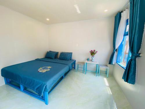 a bedroom with a blue bed and two tables at Biển Ngọc Homestay Đảo Bé Lý Sơn in Quang Ngai