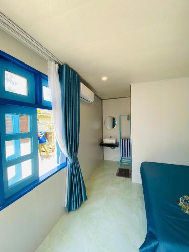 a bedroom with a blue curtain and a window at Biển Ngọc Homestay Đảo Bé Lý Sơn in Quang Ngai