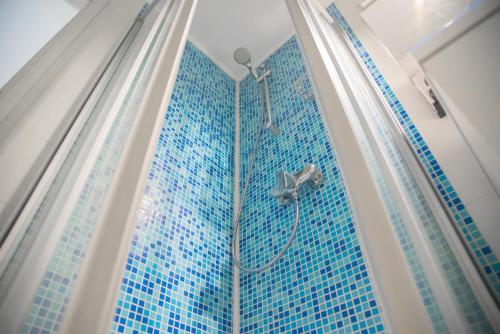ein Bad mit einer Dusche und einer blau gefliesten Wand in der Unterkunft Sobe Novi grad in Osijek