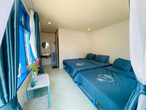 two beds in a small room with blue sheets at Biển Ngọc Homestay Đảo Bé Lý Sơn in Quang Ngai
