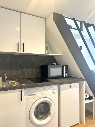 une cuisine avec un lave-linge et un micro-ondes dans l'établissement Stylish Loft Studio in Central Paris in Clery 4, à Paris
