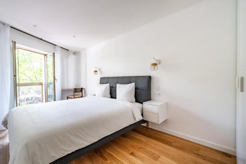 une chambre blanche avec un grand lit et une fenêtre dans l'établissement La Suite des Ternes, à Paris