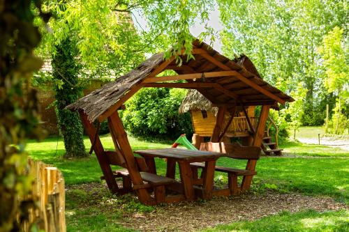 a wooden structure with a bench and a gazebo at Au pied du frêne in Herzeele