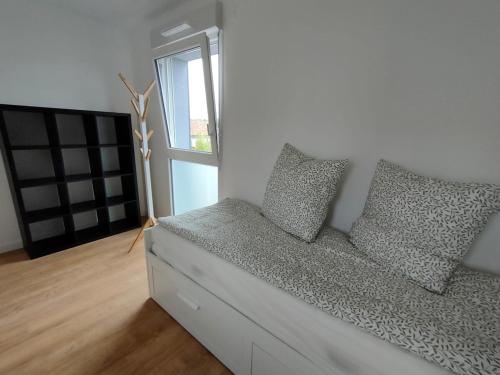 - un canapé blanc avec des oreillers dans une chambre avec une fenêtre dans l'établissement Lou Cantoun Villa neuve 6 à 8 personnes, à Saubion