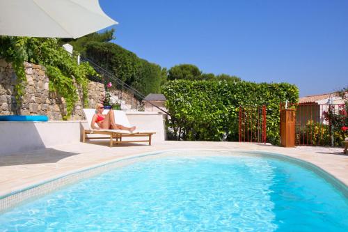 a woman sitting in a chair next to a swimming pool at Villa Le Port d'attache in Vallauris