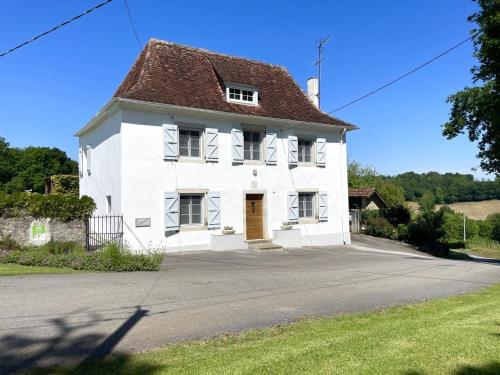 a white house with a brown roof on a street at Etchechoury in Moncayolle-Larrory-Mendibieu