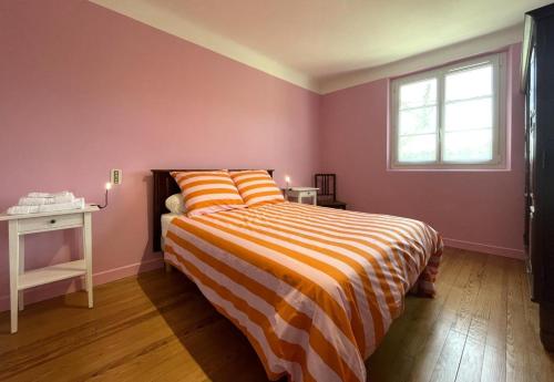 a bedroom with a bed with an orange and yellow striped blanket at Etchechoury in Moncayolle-Larrory-Mendibieu