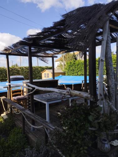 une pergola avec des tables et des chaises dans la cour dans l'établissement Au bois flotté - tiny house, à Marennes