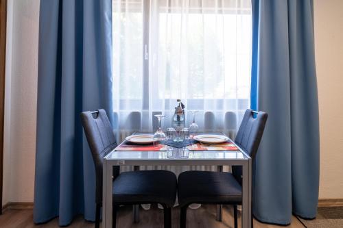 a dining table with chairs and a window with blue curtains at NEW Gästehaus Flora,Kitchen,TV,Free Parking,near Europa Park and Strasbourg in Hohberg