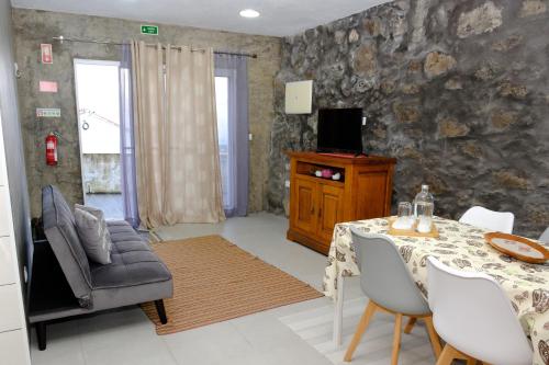 a living room with a table and chairs and a tv at Quinta da Baía - AL in Arrife