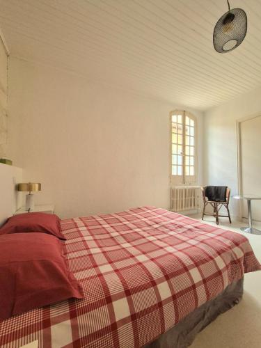 - une chambre dotée d'un lit avec une couverture tressée et une chaise dans l'établissement La Maison des Artistes, à Arles
