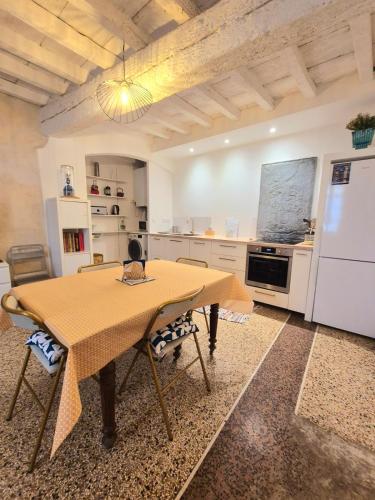 une cuisine avec une table avec des chaises et un réfrigérateur dans l'établissement La Maison des Artistes, à Arles