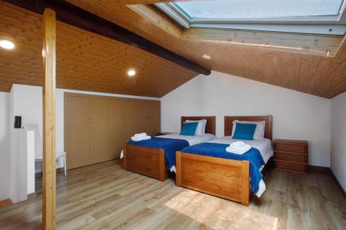 a attic bedroom with two beds and a skylight at Moradia Dos Castelos Azul in Ourém