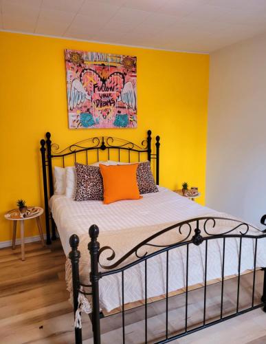 a bedroom with yellow walls and a bed with orange pillows at Motel Abricafé in Stoneham