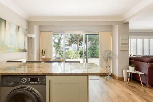 a kitchen with a washing machine and a living room at Sandy Shores - Moments from Blue Flag Sandbanks Beach in Poole