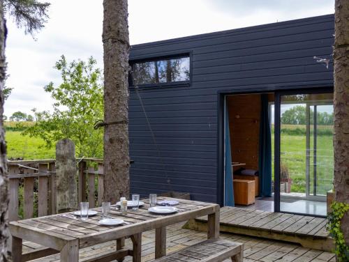 a black house with a picnic table on a deck at La Cafoutche Tiny - 5 personnes in Gommenecʼh