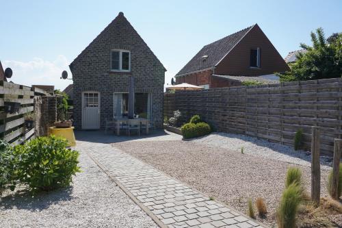a house with a retaining wall and a fence at Kustverhuur, Nieuwesluisweg 6A in Breskens
