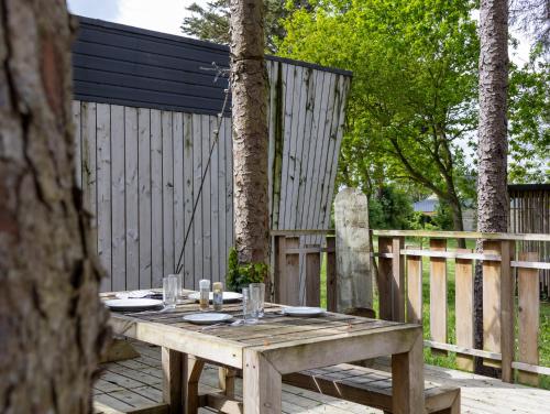 a wooden picnic table on a deck with a fence at La Cafoutche Tiny - 5 personnes in Gommenecʼh