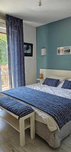 une chambre avec un grand lit avec un mur bleu dans l'établissement Olatua La vague votre havre Basque à la mer, à Saint-Jean-de-Luz
