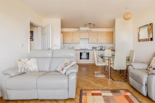 a living room with a white couch and a kitchen at Ahoy - Balcony with Beautiful Harbour Views in Poole