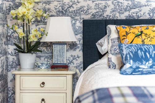 a bedroom with blue and white wallpaper and a bed with a lamp at The Old Millhouse - Luxury Retreat with Sauna, Cold Plunge, Yoga & Swim SPA in Dalkeith