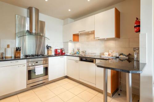 eine Küche mit weißen Schränken und einer schwarzen Arbeitsplatte in der Unterkunft Crow's Nest - On Poole Quay, Parking and Wi-Fi included in Poole